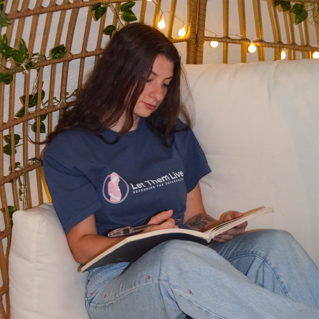 Woman reading a book on a white couch with a decorative background