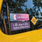 Assortment of 3 pro-life stickers on the back window of a car, including "Let Them Live Logo", "Former Fetus On Board", and "It's Okay to Like Babies Being Born".