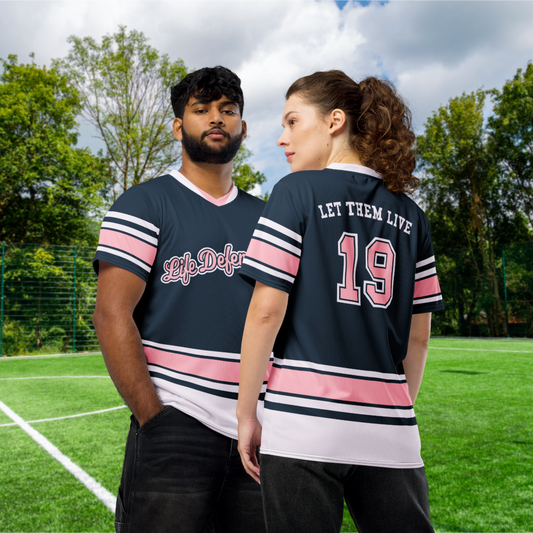 Two people wearing matching jerseys on a sports field with trees in the background